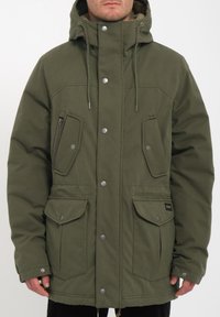Chaqueta verde oliva con un bolsillo con cremallera, dos bolsillos de solapa en la parte frontal y una capucha acogedora. Cuenta con botones a presión y cordones para ajustar.