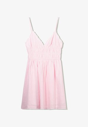 Robe sans manches rose pâle avec un décolleté en V profond, une taille smockée et des accents froncés le long des bretelles. Le tissu semble léger et texturé.
