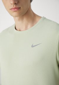 Lys grøn Nike t-shirt med rund hals og korte ærmer. Har et diskret gråt logo på den øverste venstre bryst. Struktureret stof.