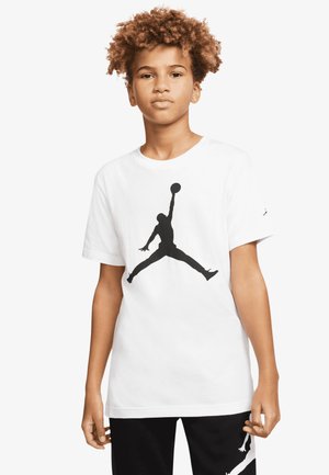 White cotton t-shirt featuring a large black Jumpman logo on the front. Short sleeves and a round neckline, paired with black pants.