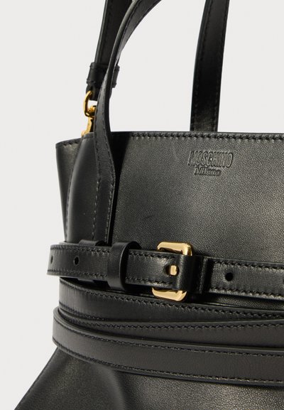 Μαύρη δερμάτινη τσάντα χειρός με χρυσή πόρπη, με δομημένο σχέδιο, λεπτομέρειες ραφής και λογότυπο Moschino ανάγλυφο στην επιφάνεια.