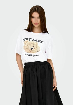 T-shirt bianco con grafica di un orsetto e testo nero; abbinato a una gonna nera ampia con vita elasticizzata. Materiale morbido e vestibilità comoda.