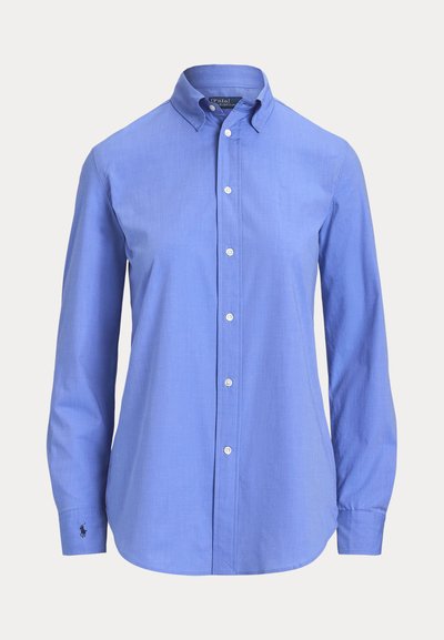 Gaišzils kokvilnas krekls ar garām piedurknēm un pogām, ar klasisku apkakli un izšuvumu ar logotipu kreisajā piedurknes daļā.