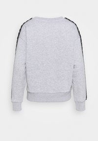 Sudadera gris claro vista desde la parte de atrás con rayas en blanco y negro que corren a lo largo de la parte superior de las mangas.