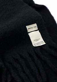 Zachte zwarte wollen sjaal met witte labels waarop "ARCTIC FOX" en "THE REYKJAVIK SCARF" staat, inclusief verzorgingsinstructies.