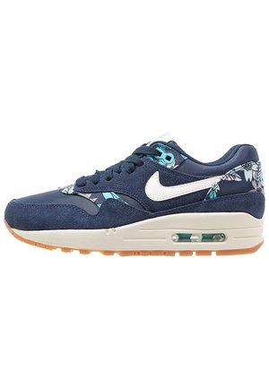 Granatowe buty sportowe Nike z białym logo, kwiatowymi wzorami, beżową podeszwą środkową z widoczną poduszką powietrzną oraz gumową podeszwą zewnętrzną.