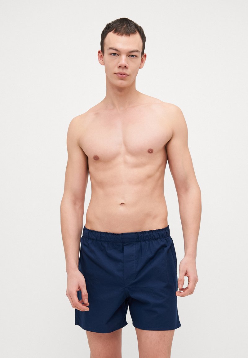 Blå badetights med elastisk midje, laget av et lett stoff, med ensfarget design og avslappet passform.