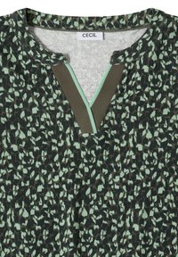 Haut à imprimé léopard vert foncé et menthe avec une encolure en forme de goutte soulignée par un liseré rayé marron et menthe, étiqueté "CECIL".