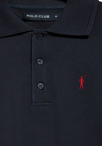 Polo shirt nera realizzata in tessuto texture con collarino a tre bottoni. Presenta un logo ricamato di un golfista rosso sul lato sinistro del petto.