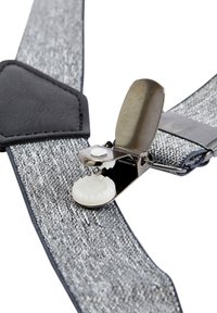 Grå tygbyxor har en metallklämma med en vit knapp. Texturerade remmar accentueras av en svart läderkoppling.