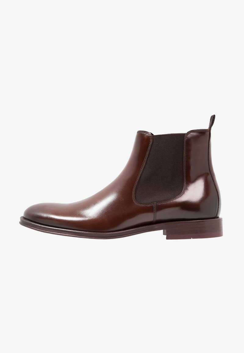 Botte Chelsea en cuir marron avec panneaux latéraux élastiques, bout arrondi, finition lisse et petit talon empilé. Design classique à hauteur de cheville.