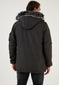 Gray padded jacket with a detachable hood featuring a faux fur trim, textured fabric, and two side pockets. Back view shows seam detailing.
