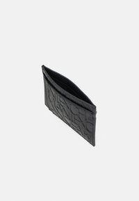 Portafoglio in pelle nera con design in rilievo, presenta una superficie texturizzata e una fessura aperta per le carte. Forma compatta e rettangolare.