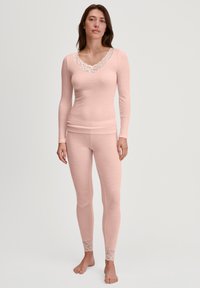 Light pink ribbed long-sleeve top with a lace V-neckline, paired with matching ribbed leggings featuring lace trim at the ankles.