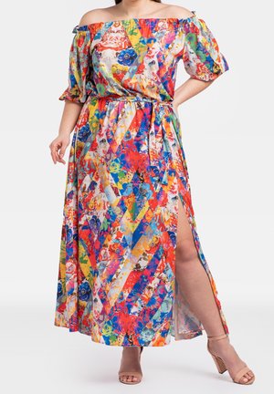 Vrouw draagt een kleurrijke off-shoulder bloemen maxi-jurk met een hoge split en nude sandalen met blokhak.