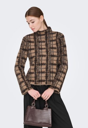 Pull en laine à carreaux marron et beige avec un col montant, des manches longues et un ourlet court. Associé à un sac à main texturé marron foncé.