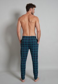Men's plaid lounge pants in dark teal and black. Soft fabric, relaxed fit, featuring an elastic waistband and side pockets.