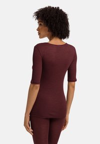Burgundowa, prążkowana bluzka z rękawami do łokci, okrągłym dekoltem i dopasowanym krojem. Tkanina ma subtelną teksturę, w połączeniu z dopasowanymi dołami.