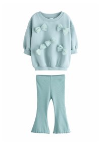 Lyseblå sweatshirt med puffede ærmer og dekorative sløjfer. Ribbede lyseblå flared leggings. Blødt stof med en struktureret overflade.