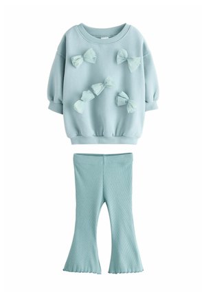 Ljusblå sweatshirt med puffärmar och dekorativa rosetter. Ribbade ljusblå utsvängda leggings. Mjuk textil med strukturerad yta.