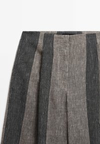 Gros plan sur un tissu en lin avec de larges rayures verticales en gris foncé et gris clair sur une jupe ou un pantalon.