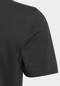 T-shirt in cotone nero con collo a giro, maniche corte e texture a costine. I dettagli delle cuciture sono visibili lungo le spalle e i bordi delle maniche.