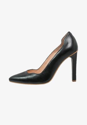 Chaussure à talons hauts en cuir noir avec un bout pointu et un design découpé sur les côtés. Le talon est élancé et mesure environ 10 cm de hauteur.