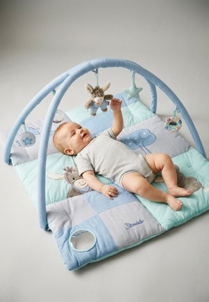 Baby lying on blue padded play mat with hanging soft toys shaped like a donkey, star, and rattle.