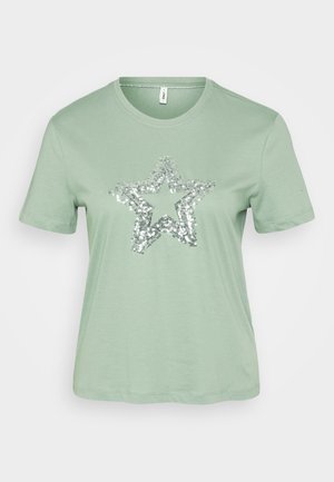 T-shirt verde menta de manga curta com um grande design de estrela em lantejoulas prateadas na frente. Feita de um tecido de algodão leve e macio.