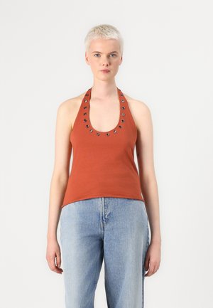 Rust-colored tank top with a scoop neck, featuring metallic studs along the neckline. The fabric is smooth, paired with light blue jeans.