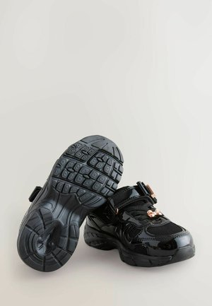Scarpe nere in pelle verniciata con una tomaia testurizzata, suole in gomma con un motivo antiscivolo, cinturino regolabile e un accento metallico.