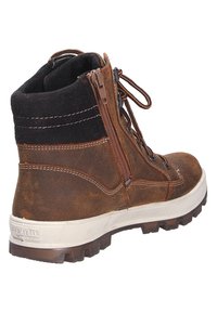 Botte en cuir marron et en suède noir mi-mollet avec une semelle en caoutchouc blanche, dotée d'une fermeture éclair sur le côté et de lacets marron. Tige texturée et talon renforcé.