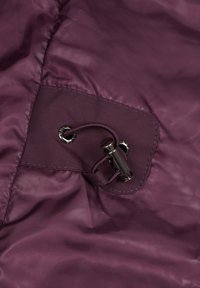 Bordeauxfarbener Jackenstoff mit einer dekorativen Schlaufe und einem Toggle-Verschluss, glatter, glänzender Textur und sichtbaren Nähdetails.