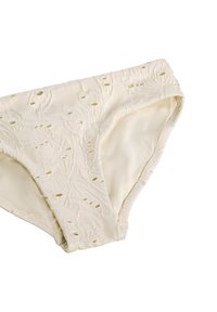 Μπικίνι κάτω μέρους κρέμας απόχρωσης με υφή που διαθέτει λουλουδάτα σχέδια και μικρές λεπτομέρειες με κοπή, απομονωμένο σε λευκό φόντο.