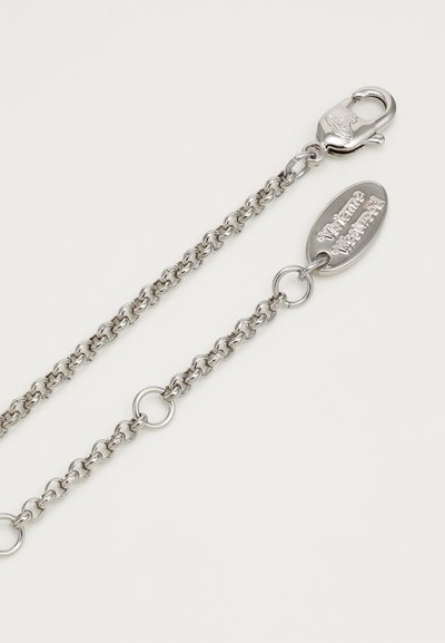 Hõbedane metallketi, millel on omavahel seotud lingid, klamber ja ovaalne silt graveeritud tekstiga. Sile tekstuur ja poleeritud viimistlus.