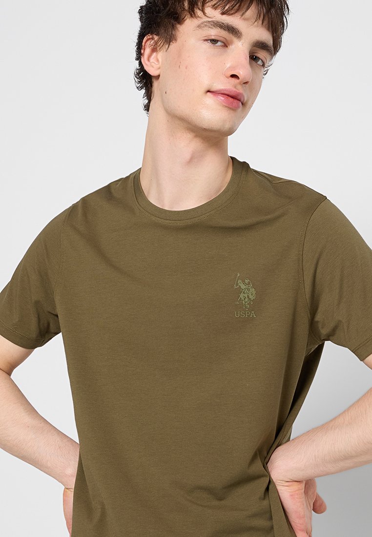 Olivegrünes Baumwoll-T-Shirt mit Rundhalsausschnitt, kurzen Ärmeln und einem dezenten gestickten Logo auf der Brust. Angenehme Textur und lässige Passform.