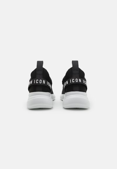 Scarpe sportive nere con tomaia in maglia, suola in gomma bianca e linguetta sul tallone. Presentano il testo ripetuto "ICON" sulla fascia elastica, design minimalista.