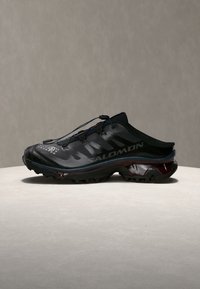 Μαύρο slip-on αθλητικό παπούτσι Salomon με ανθεκτική σόλα και γρήγορο σύστημα κορδονιών, εμφανίζεται πλευρικά σε ουδέτερο φόντο.