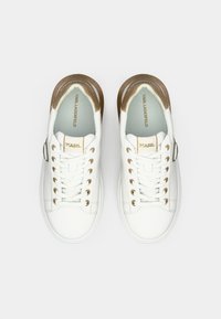 Białe skórzane trampki ze złotymi akcentami, zaokrąglonym noskiem i płaskimi sznurówkami. Posiadają teksturowany złoty obcas oraz wkładkę z logo. Przeźroczyste oczka są metaliczne.