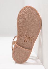 Suela de caucho color tostado con superficie texturizada, que presenta una marca grabada y el tamaño. Diseño minimalista con forma curva y bordes suaves.