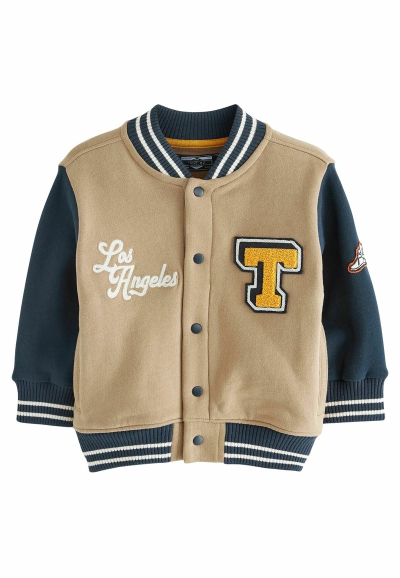 Veste universitaire beige et bleu marine avec fermeture à boutons. Comprend le mot brodé "Los Angeles" et un écusson jaune en forme de lettre "T". Poignets côtelés.