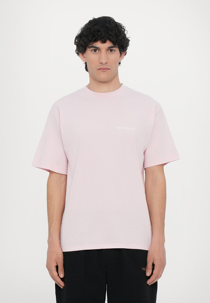 Helles rosa Baumwoll-T-Shirt mit kurzen Ärmeln, Rundhalsausschnitt und einem kleinen weißen "No Problemo"-Textlogo auf der Brust.