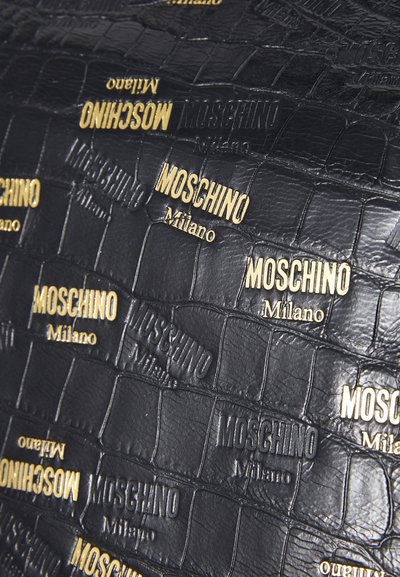 Geantă din piele neagră cu un efect de relief, având logo-uri ridicate de aur "Moschino Milano" și un model de crocodil pe întreaga suprafață. Textură netedă și design structurat.