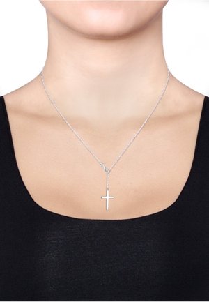 Silberne Kettenhalskette mit einem Kreuzanhänger, der ein strukturiertes Design aufweist, hängt in einer Y-Form von einer Schlaufe auf einem schwarzen Oberteil.