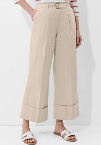 Beige weite Hose mit hohem Bund, Falten und einem taillierten Design. Verfügt über eine saubere, glatte Textur und einen umgeschlagenen Saum.