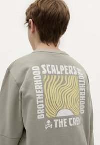 Grijze ronde hals sweatshirt met een grote grafische print op de rug met zonnestralen en tekst, gemaakt van zachte, textuurrijke stof.