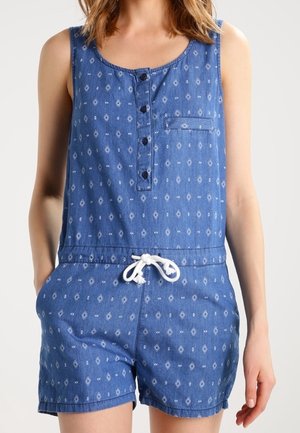 Combinaison en jean avec un col en U, patte de boutonnage et sans manches. Dotée d'une taille à cordon et d'un motif en losanges sur l'ensemble.