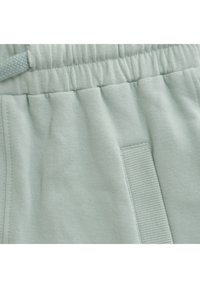 Ljusmyntgrön sweatpants med mjuk textur, elastisk midja med dragsko och en distinkt horisontell sömdetalj.
