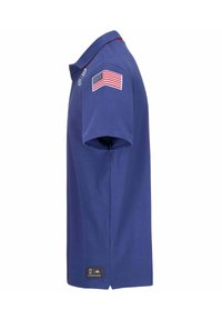 Polo shirt blu in cotone. Presenta un colletto rosso, una patch con la bandiera americana sulla manica e un'etichetta con il marchio sull'orlo.