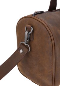 Bruine leren tas met een afgeronde vorm, voorzien van een metalen gesp en een stevige hengsel. Zichtbare stiksels en een subtiele glans op het oppervlak.